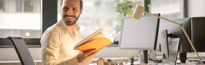 smiling person with open book at desk