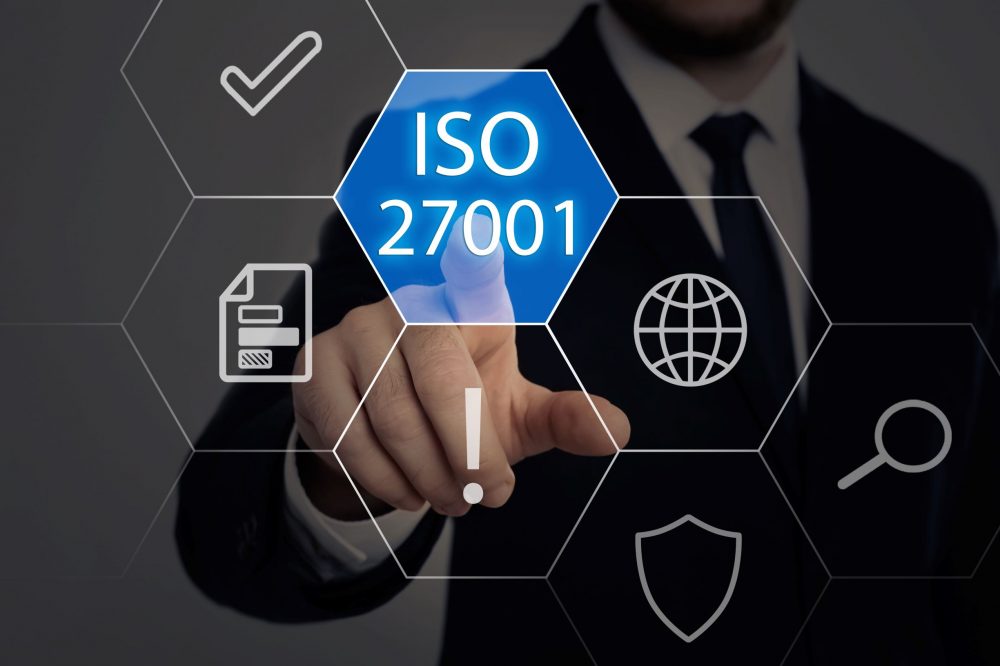 ISO 27001 selected on hexagonal tile by businessperson, business concept